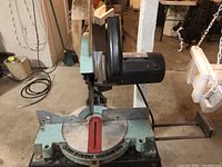 Close-up showing blade guard, miter gauge, and motor housing of Delta chop saw.