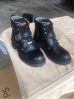 Pair of black leather Harley Davidson boots for women size 7.5, shown from angled front view on cloth surface.