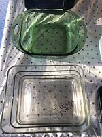 Top view of two glass Pyrex baking dishes, one green with handles and one clear rectangular dish with marking visible inside.