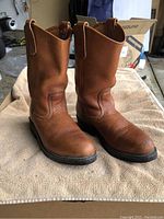 Pair of light brown Redwing cowboy boots standing upright on towel, showing front and side views.