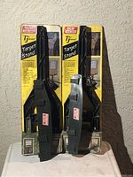 View of two black plastic MTM Case-Gard T Jammit target stands in original yellow and black packaging, showing front of stands with packaging labels distinct and clear.