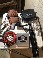 White table with GVM LED panel, orange gel filters, cables, audio interface, battery pack and handle