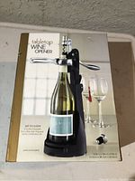 Tabletop wine opener set displayed on a table, with bottle inserted demonstrating use, includes visible accessories from packaging.