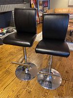 Two stools front view showing black seats and chrome pedestal bases