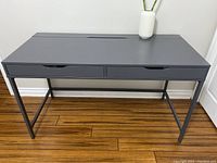 Front view of gray IKEA desk with two drawers, showing clean surface and metal base frame.