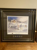 Full view of the framed print showing the vintage hockey scene with black and gold frame on wooden floor.