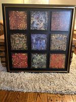 Full view of framed wooden art panel with square grid design showing nine colorful, textured art sections.
