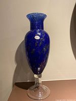 Full view of the tall blue Murano glass vase with clear base