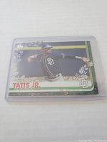 Front of Fernando Tatis Jr. baseball rookie card in protective sleeve, showing player in action with San Diego Padres uniform and decorative border.