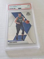 Front side of the Luka Doncic graded basketball card in PSA slab showing player dribbling in team uniform with mosaic background