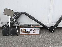 Photo showing the Swagman 4-bike rack hitch parts including the main hitch frame and mounting plates, the dual action bike seat, pair of wide view auto mirrors with black supports, and the boxed American Builder wet & dry auto vacuum placed on pavement.