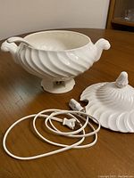 White ceramic electric soup tureen with swirled design, lid removed showing interior and ladle, electrical cord visible.
