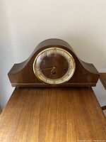 Front view of Forestville mantel clock showing wooden casing and gold-tone numbered dial behind glass.