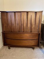 Front view of tallboy dresser showing upper grooved doors and curved lower drawers