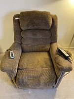 Front view of brown powered medical recliner lift chair with wired remote on armrest, showing well worn seat and fabric condition