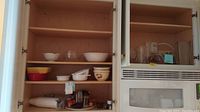 Overview of two cabinets containing assorted bowls, glass vases, and Corning Ware dishes