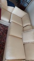 Two-piece beige sofa set with loose cushions and one matching pillow. Fabric shows textured geometric pattern.