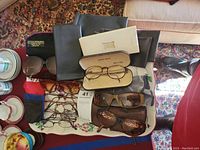Photo showing the full lot on a floral tray, including various eyeglasses, sunglasses, cases, and cleaning cloths.