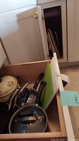 Dresser drawer containing Calphalon pots and pans with lids, a ceramic pot, and cutting boards.