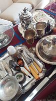 Image showing various silver plated trays, utensils, goblets, sugar bowl, butter dish on displaying surface