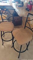 Two stools with black metal frames and beige velour swivel seats placed near kitchen counter.