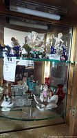 Display cabinet shelves showing porcelain figurines, vases, and various decorative items.