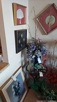 Overview of the corner wall displaying four framed art pieces arranged vertically and diagonally, with floral and botanical décor on a small table below them.