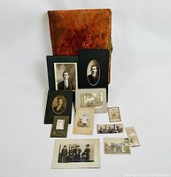 Photo of antique red velvet Victorian photo album with metal clasp, includes extra cabinet card photos and loose prints in front