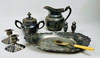 Full lot image showing each item including jug, sugar bowl, salt & pepper shakers, bread platter, butter knife, and candle holders on a neutral surface.
