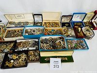 Wide view of multiple open jewelry boxes filled with assorted bracelets, necklaces, brooches, rings and earrings
