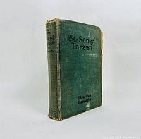 Front cover of the green cloth hardcover with black lettering showing wear and fraying on spine and edges.