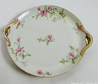 Top view of one round Haviland Limoges plate with pink rose designs and two gold-accented handles on rim.