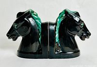 Side by side frontal view of the pair of glossy black and green glazed horsehead bookends.