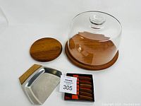 Photo showing the cake stand/cheese tray with glass dome, crumb catcher with teak handle, and set of six cheese knives with teak handles.