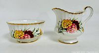 Photo of the Paragon carnation-themed creamer and sugar bowl pair showing front and side views with bright floral design and gold edges.