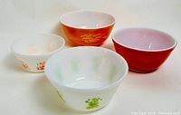 Four vintage mixing bowls arranged in a group: two Pyrex and two Federal circus-themed bowls.