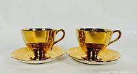 Pair of gold-colored ribbed tea cups with matching saucers