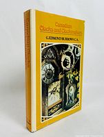 Angled front cover view showing yellow dust jacket and antique clock photo collage