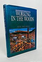 Front cover of 'Working in the Woods' book by Ken Drushka, showing colorful logging scene and title details.