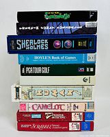 Stacked game boxes photo showing titles: Lemmings (no discs), Sherlok Holmes, Hoyle's Book of Games, PGA Tour Golf, Camelot, Clue Master Detective, Scrabble.