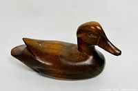 Side profile photo of a polished wooden mallard duck decoy showing the full body and head with a smooth wood grain finish.