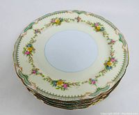 Stacked view of six Noritake Goldconda dinner plates showing floral and gold trim pattern