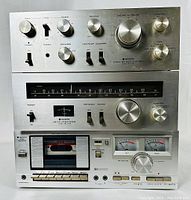 Front view of stacked amplifier, tuner, and cassette deck showing controls and meters