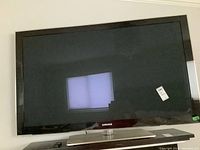 Full front view of Samsung 58 inch plasma TV showing black bezel screen and stand