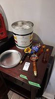 Beer keg pulls on wooden table with metal tin and lid.
