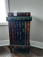 Front view of cabinet shaped like stacked books, showing spines and top book title.