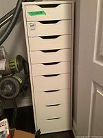 Full front view of the tall white cabinet with nine drawers, showing overall design and wear.