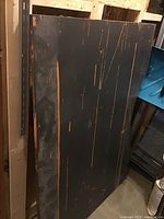 Black painted wooden table top leaning against shelf