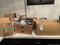 Boxes containing various light fixtures, dimmer switches, and electrical hardware items in a basement room.