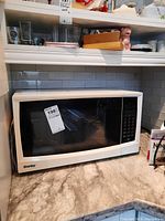 White Danby microwave oven placed on kitchen counter with visible brand and model label.
